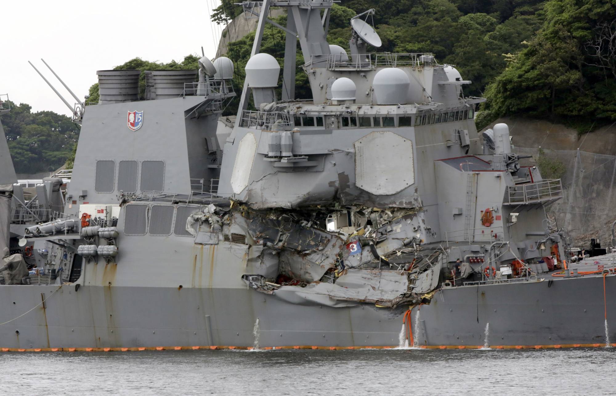 FILE - In this June 18, 2017, file photo, the damaged USS Fitzgerald is docked at the U.S. Naval base in Yokosuka, southwest of Tokyo, after colliding with Philippine-flagged container ship ACX Crystal off Japan.  On June 17, 2017, seven sailors died after a container ship collided with the USS Fitzgerald guided-missile destroyer off Japan. (AP Photo/Eugene Hoshiko, File)