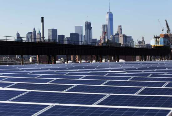 In this Feb. 14, 2017 photo, a rooftop is covered with solar panels at the Brooklyn Navy Yard in New York. The Manhattan skyline is at top. Cheap solar panels imported from China and other countries have led to a boom in the U.S. solar industry, where rooftop and other installations have surged 10-fold since 2011.   (AP Photo/Mark Lennihan)