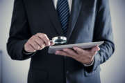 Businessman holding magnifying glass and digital tablet