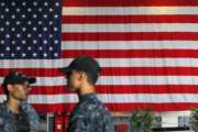 U.S. Navy servicemen stand in front of an American national flag at the USS Ronald Reagan aircraft carrier in Hong Kong, Monday, Oct. 2, 2017. A senior U.S. Navy commander of the nuclear powered aircraft carrier reportedly participating in joint drills with South Korea later this month told reporters during a stop in Hong Kong on Monday that his strike group is committed to defending U.S. allies in the region. (AP Photo/Vincent Yu)