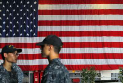 U.S. Navy servicemen stand in front of an American national flag at the USS Ronald Reagan aircraft carrier in Hong Kong, Monday, Oct. 2, 2017. A senior U.S. Navy commander of the nuclear powered aircraft carrier reportedly participating in joint drills with South Korea later this month told reporters during a stop in Hong Kong on Monday that his strike group is committed to defending U.S. allies in the region. (AP Photo/Vincent Yu)