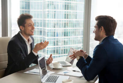 Candid businessman sharing his opinion about work with colleague, telling interesting story when having conversation with partner on coffee-break, making successful negotiation with investor in office
