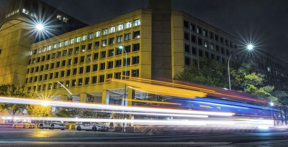 Traffic along Pennsylvania Avenue in Washington streaks past the Federal Bureau of Investigation headquarters building Wednesday night, Nov. 1, 2017. Scores of U.S. diplomatic, military and government figures were not told about attempts to hack into their emails even though the FBI knew they were in the Kremlin’s crosshairs, The Associated Press has learned. (AP Photo/J. David Ake)