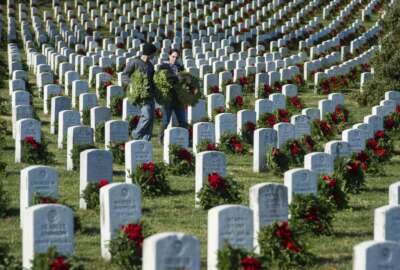 Marine Corp SSGT Andrew Christman, left, and Ashley Robinson, of Chambersburg, Pa., carry wreaths as they participate in Wreaths Across America, placing remembrance wreaths on headstones at Arlington National Cemetery, Arlington, Va., Saturday, Dec. 16, 2017. (AP Photo/Cliff Owen)