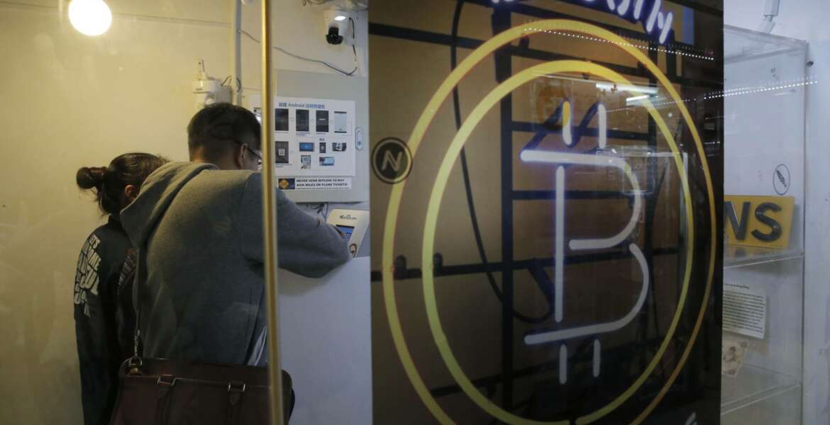 In this Friday, Dec. 8, 2017, photo, people use the Bitcoin ATM in Hong Kong. The launch of a U.S. futures contract for bitcoin on Sunday, Dec. 10, 2017, underscores the virtual currency's increasing mainstream acceptance, including in many parts of Asia, where it already has a wide following among speculators and investors. (AP Photo/Kin Cheung)