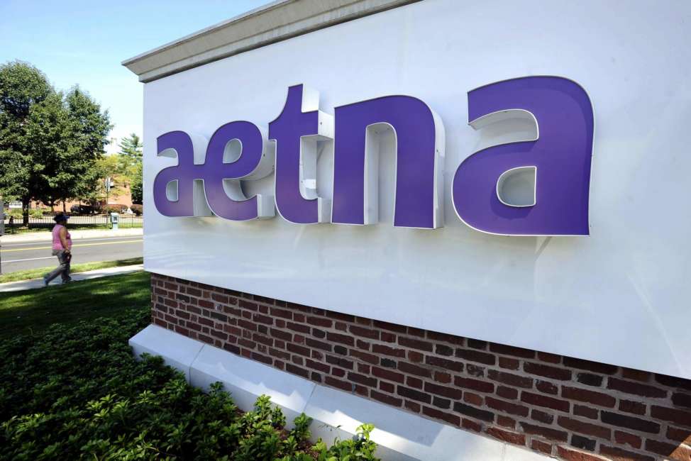 FILE - In this Aug. 19, 2014, file photo, a pedestrian walks by a sign at Aetna headquarters in Hartford, Conn. CVS Health, the second-largest U.S. drugstore chain, is buying Aetna, the third-largest health insurer. The evolution won't happen overnight, but in time, shoppers may find more clinics in CVS stores and more services they can receive through the network of nearly 10,000 locations that the company has built. (AP Photo/Jessica Hill, File)