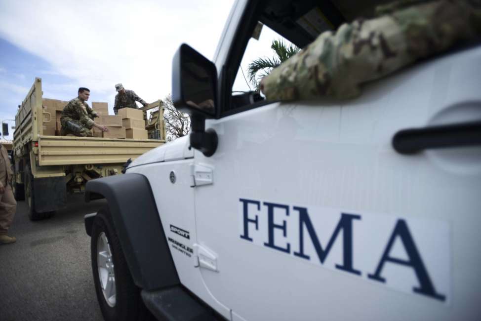 FILE - In this Oct. 5, 2017 file photo, Department of Homeland Security personnel deliver supplies to Santa Ana community residents in the aftermath of Hurricane Maria in Guayama, Puerto Rico. The U.S. Federal Emergency Management Agency (FEMA) is rejecting on Monday, Dec. 18, 2017  a report by Refugees International criticizing local and federal hurricane response in Puerto Rico. (AP Photo/Carlos Giusti, File)