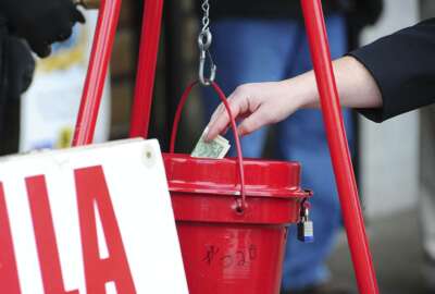 FILE - In this Nov. 22, 2017, file photo, a patron donates money in a Salvation Army red kettle in Wilkes-Barre, Pa. In this season of giving, charity seems to be getting an extra jolt because the popular tax deduction for charitable donations will lose a lot of its punch.  (Mark Moran/The Citizens' Voice via AP)