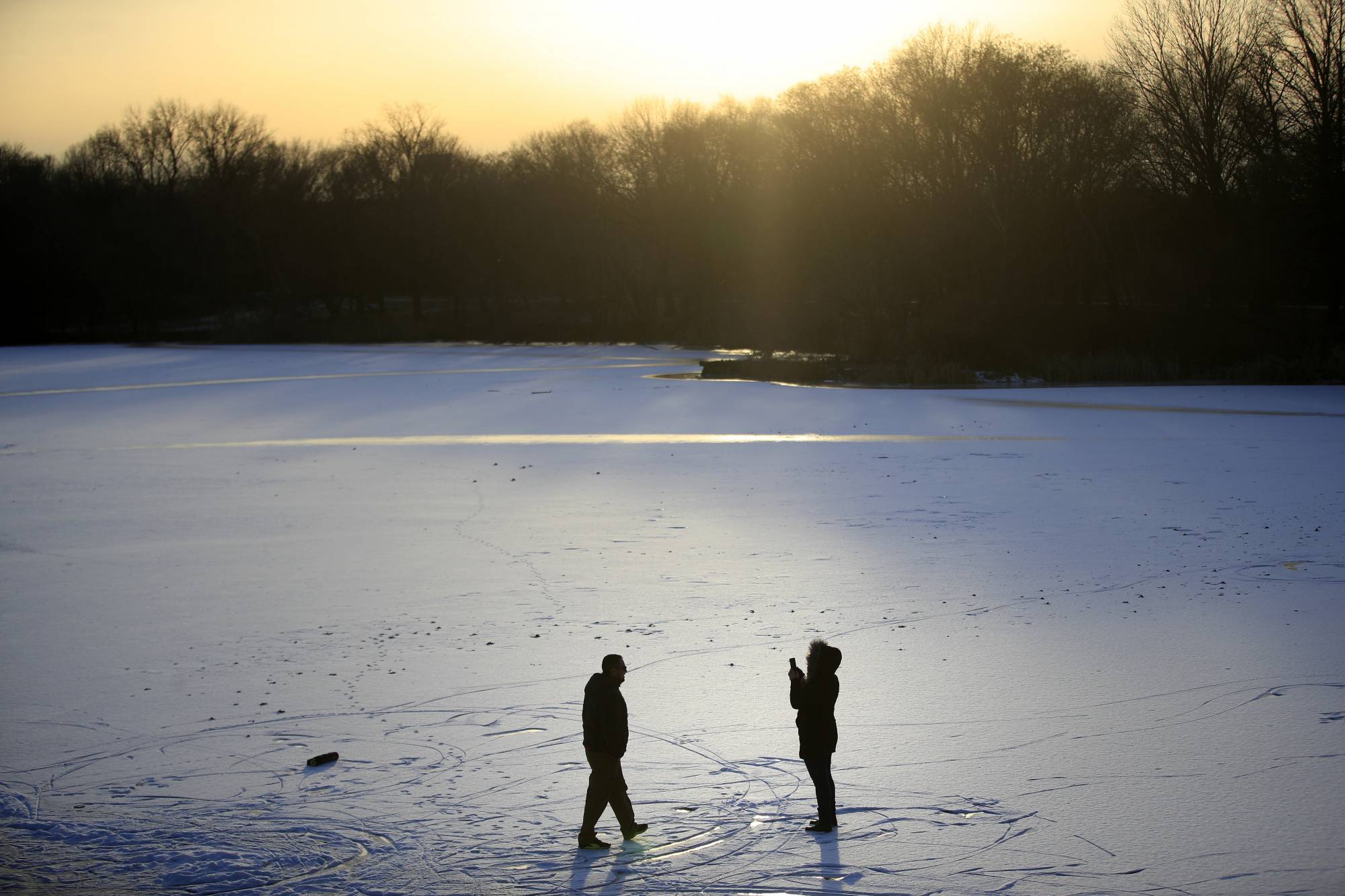 A couple takes photographs on a frozen pond at Franklin Delano Roosevelt Park in Philadelphia, Wednesday, Jan. 3, 2018. (AP Photo/Matt Rourke)
