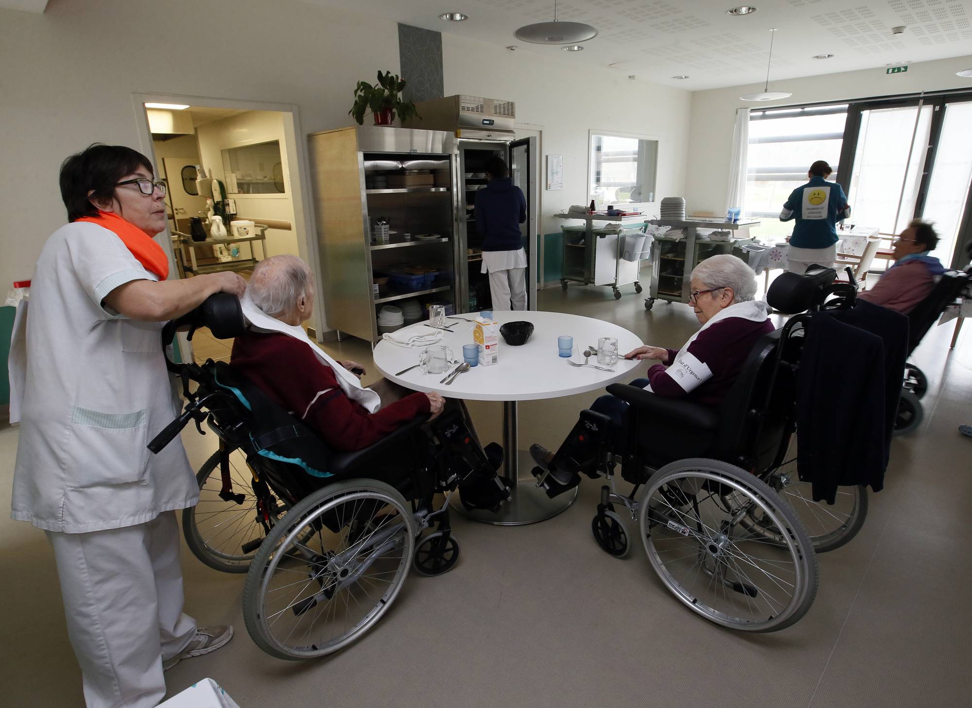 A care worker takes care to residents of the Maharin nursing home of Anglet, southwestern France, Tuesday, Jan.30, 2018. French care workers are protesting at nursing homes around the country in anger over staff shortages and cost cuts. Unions say workers are under increasing pressure to cut corners on feeding, cleaning and hygiene care for elderly residents. (AP Photo/Bob Edme)