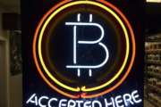 In this Feb. 7, 2018, photo, a neon sign hanging in the window of Healthy Harvest Indoor Gardening in Hillsboro, Ore., shows that the business accepts bitcoin as payment. Purchases with bitcoin and other digital currencies remain rare relative to cash and credit cards. (AP Photo/Gillian Flaccus)