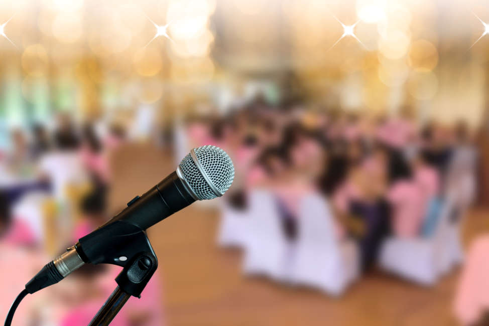 Microphone on boom stand  ready for the meeting ,blurred background group of people sitting around table.