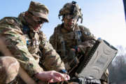 Sgt. 1st Class Joseph Rombold (left), an observer coach at Hohenfels Training Area, Germany, shows Spc. William Ritter (right), a military policeman with 287th Military Police Company, 97th Military Police Battalion, 89th Military Police Brigade, Fort Riley, Kansas, how to properly set up the system to operate the RQ-11 Raven, a small unmanned aerial system (sUAS), during Allied Spirit VIII at Hohenfels, Germany, Jan. 26, 2018. Roughly 4,100 troops from 10 nations are participating in Allied Spirit VIII, a multinational training exercise designed to test participants' readiness and capabilities. 