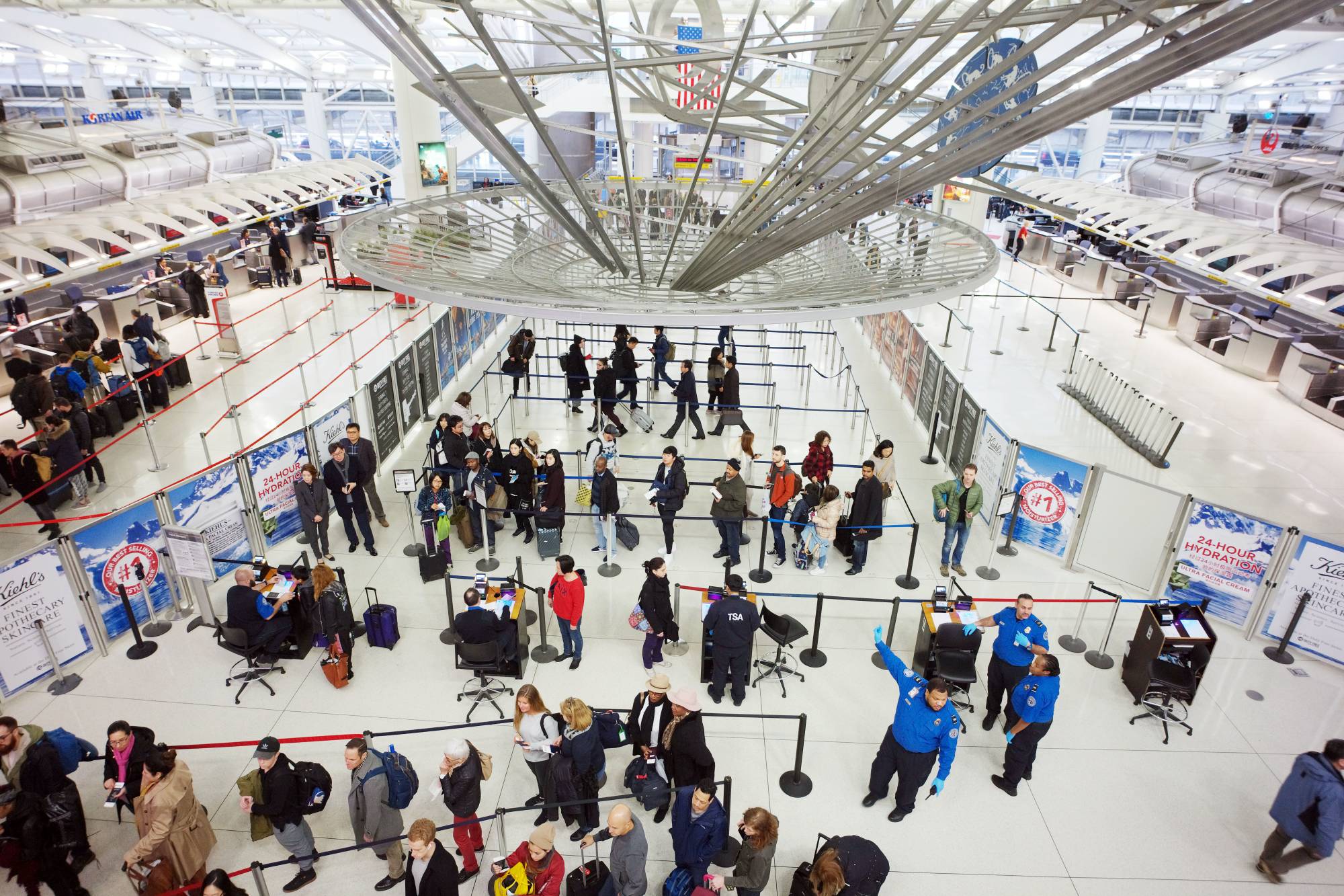 FILE- In this March 2, 2018, file photo, passengers stand in line as they wait to pass through a TSA security checkpoint at JFK International Airport in New York. If time is money, find out whether your credit card will reimburse you the application fee for TSA PreCheck or Global Entry programs. These programs can offer faster clearance through airport screening, and some cards offer application credits of up to $100. (AP Photo/Mark Lennihan, File)