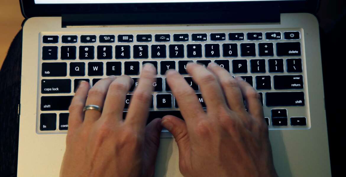 FILE - This June 19, 2017, file photo shows fingers on laptop keyboard in North Andover, Mass. Americans appear to be heeding expert advice for keeping their passwords and accounts safe. A new poll by The Associated Press and the NORC Center for Public Affairs Research finds that 41 percent of Americans use unique passwords for most or all online services. (AP Photo/Elise Amendola, File)