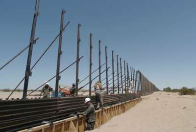 FILE - In this June 8, 2006, file photo, members of the National Guard work on construction of a border wall at the U.S.-Mexico border next to San Luis Rio Colorado, Mexico. Photo was taken from a few steps into the United States. The arrival of U.S. National Guard troops in Arizona has scared off illegal Mexican migrants along the border as a whole, significantly reducing crossings, according to U.S. and Mexican officials. From 2006 to 2008, the Guard fixed vehicles, maintained roads, repaired fences and performed ground surveillance. (AP Photo/David Maung, File)