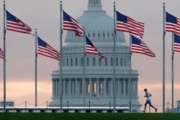 FILE - In this Sept. 27, 2017, file photo, a early morning runner crosses in front of the U.S. Capitol as he passes the flags circling the Washington Monument in Washington. Congress returns from spring break Monday, April 9, 2018,  scrambling to compile a to-do list that will satisfy a president they desperately need to be touting their achievements, not undermining them, as they prepare to hit the campaign trail. (AP Photo/J. David Ake, File)