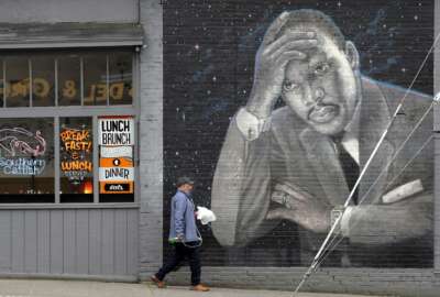 A man walks past a large mural of the Rev. Martin Luther King Jr. on the side of a diner, painted by artist James Crespinel in the 1990's and later restored, along Martin Luther King Jr. Way, Tuesday, April 3, 2018, in Seattle. The civil rights leader was killed 50 years ago Wednesday in Memphis. Seattle events commemorating his assassination will be held Wednesday evening at Mt. Zion Baptist Church. (AP Photo/Elaine Thompson)