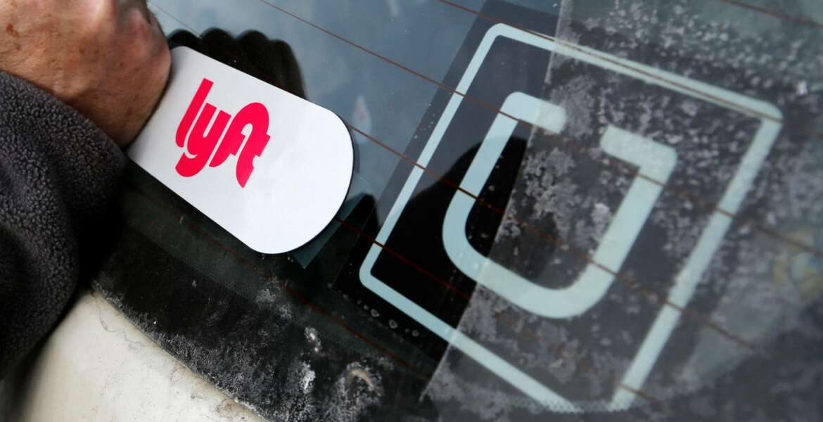 FILE- In this Jan. 31, 2018, file photo, a Lyft logo is installed on a Lyft driver's car next to an Uber sticker in Pittsburgh. Uber and Lyft drivers might seem well-insured, between the ride-booking companies’ coverage and their own policies. However, a crucial gap leaves drivers at risk if they have an accident at the wrong time. (AP Photo/Gene J. Puskar, File)