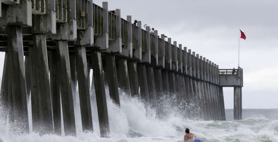 A surfer makes his way out into the water as a subtropical approaches on Monday, May 28, 2018, in Pensacola, Fla. The storm gained the early jump on the 2018 hurricane season as it headed toward anticipated landfall sometime Monday on the northern Gulf Coast, where white sandy beaches emptied of their usual Memorial Day crowds. (AP Photo/Dan Anderson)