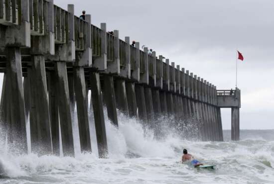 A surfer makes his way out into the water as a subtropical approaches on Monday, May 28, 2018, in Pensacola, Fla. The storm gained the early jump on the 2018 hurricane season as it headed toward anticipated landfall sometime Monday on the northern Gulf Coast, where white sandy beaches emptied of their usual Memorial Day crowds. (AP Photo/Dan Anderson)