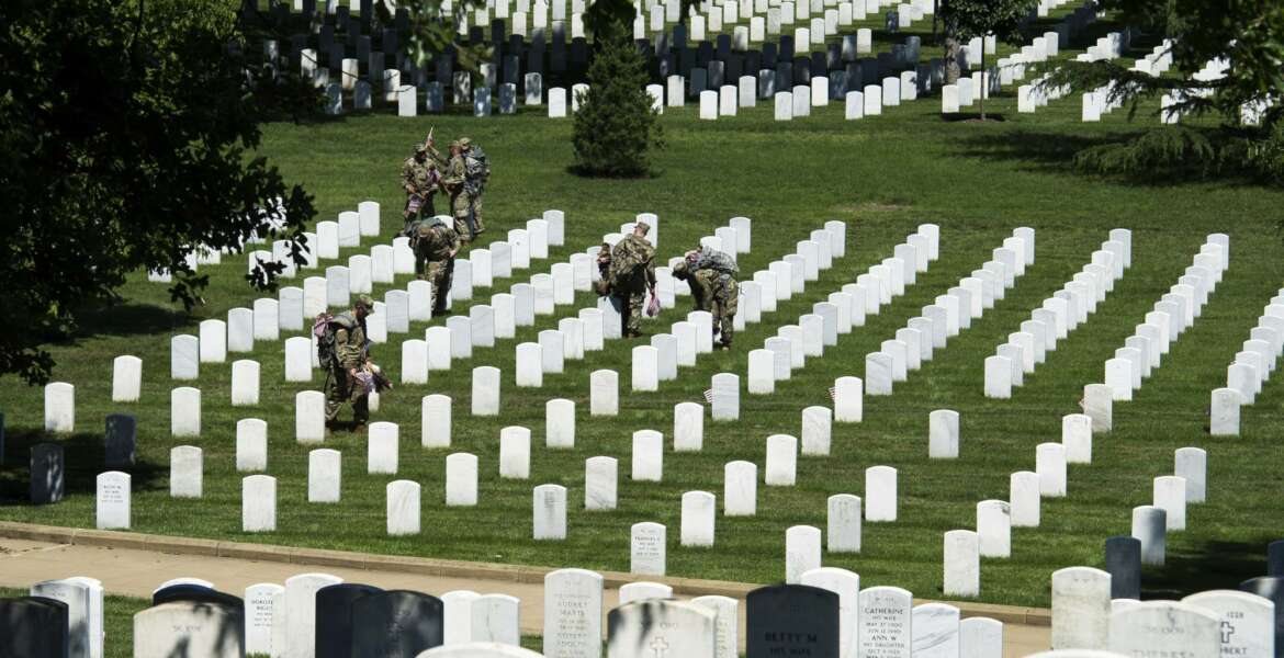 Members of the Army 3d U.S. Infantry Regiment, The Old Guard, place flags at the headstone of fallen military members during its annual Flags In ceremony at Arlington National Cemetery, May 24, 2018, in Arlington, Va. (AP Photo/Cliff Owen)