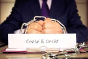 Cease and desist hands of a businessman are chained by a chain as a symbol of the cessation of illegal actions.