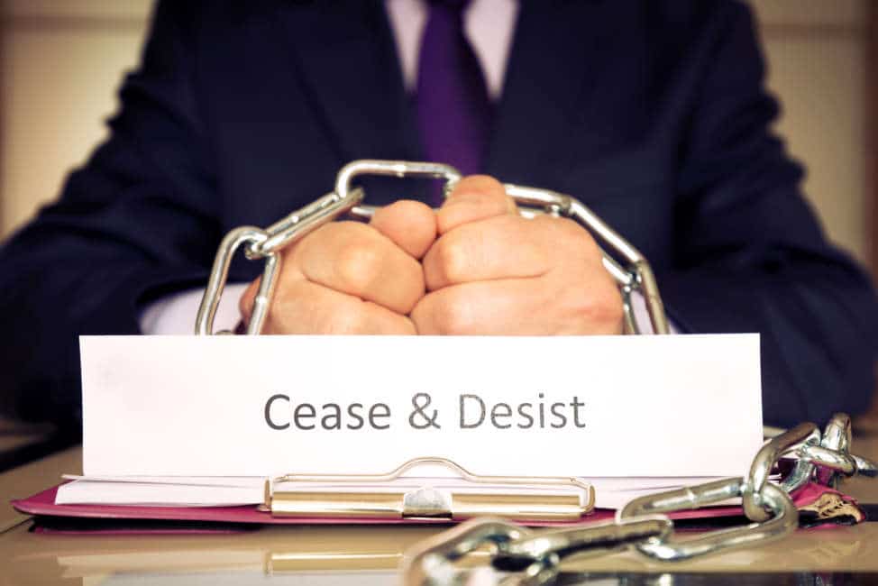 Cease and desist hands of a businessman are chained by a chain as a symbol of the cessation of illegal actions.