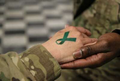 U.S. Army Sgt. 1st Class Tyrone Lawrence, right, places a temporary teal ribbon tattoo on a Soldier's hand at the Koele dining facility at Bagram Airfield in Parwan province, Afghanistan, April 2, 2014. The teal ribbon was the symbol of sexual assault survivors and awareness. (DoD photo by Staff Sgt. Kelly Simon, U.S. Army/Released)

