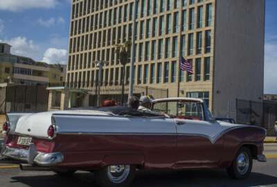 FILE - In this Oct. 3, 2017, file photo, tourists ride a classic convertible car on the Malecon beside the United States Embassy in Havana, Cuba. Medical tests have confirmed that one additional U.S. Embassy worker has been affected by mysterious health incidents in Cuba, bringing the total number to 25. That's according to an unclassified notice sent to congressional officials by the State Department. (AP Photo/Desmond Boylan, File)