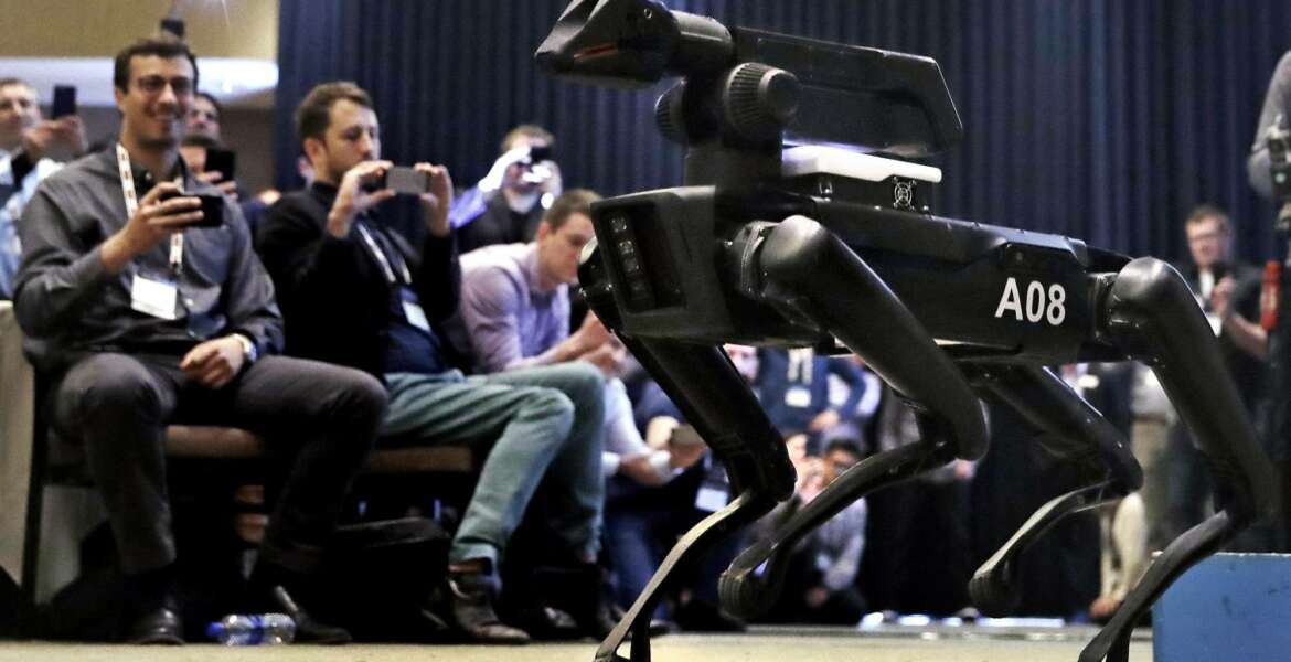 In this Thursday, May 24, 2018, photo, a Boston Dynamics SpotMini robot is walks through a conference room during a robotics summit in Boston. It's never been clear whether robotics company Boston Dynamics is making killing machines, household helpers, or something else entirely. But the secretive firm, which for nine years has unnerved viewers with YouTube videos of robots that jump, gallop or prowl like animal predators, is starting to emerge from a quarter-century of stealth. (AP Photo/Charles Krupa)