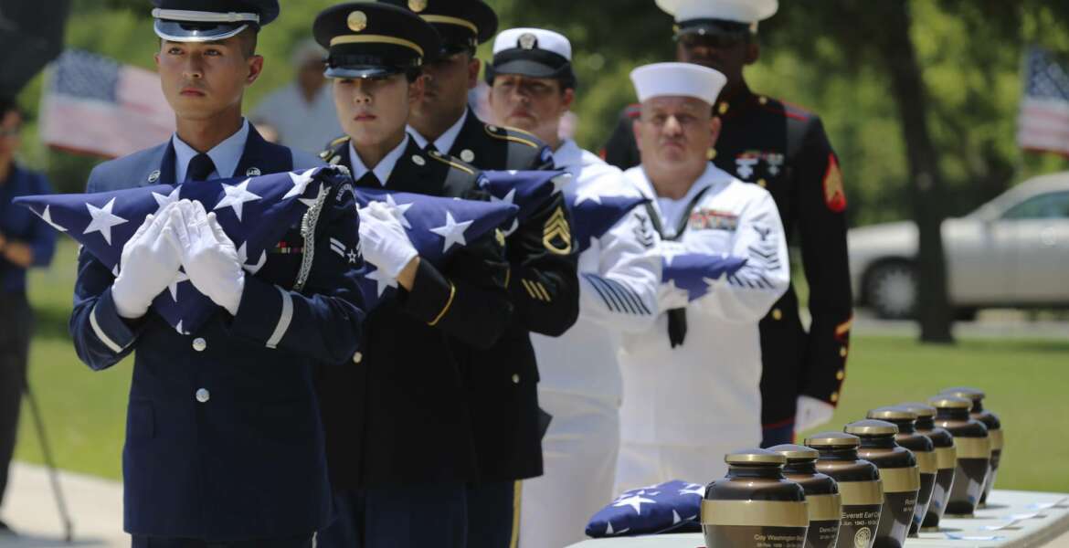 In this Friday, June 1, 2018 photo, military service members with the Armed Services Honor Guard prepare to present folded flags as Fort Sam Houston National Cemetery and the Missing In America Project conduct a military burial service for the cremated remains of eight unclaimed veterans in San Antonio.  The remains of eight U.S. military veterans that for years had been stored in the basement of a county courthouse in the Texas Panhandle have been interred as part of a formal ceremony in San Antonio. (Kin Man Hui/The San Antonio Express-News via AP)