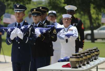 In this Friday, June 1, 2018 photo, military service members with the Armed Services Honor Guard prepare to present folded flags as Fort Sam Houston National Cemetery and the Missing In America Project conduct a military burial service for the cremated remains of eight unclaimed veterans in San Antonio.  The remains of eight U.S. military veterans that for years had been stored in the basement of a county courthouse in the Texas Panhandle have been interred as part of a formal ceremony in San Antonio. (Kin Man Hui/The San Antonio Express-News via AP)