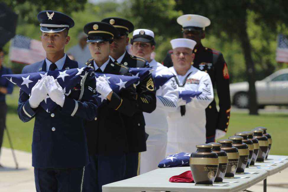 In this Friday, June 1, 2018 photo, military service members with the Armed Services Honor Guard prepare to present folded flags as Fort Sam Houston National Cemetery and the Missing In America Project conduct a military burial service for the cremated remains of eight unclaimed veterans in San Antonio.  The remains of eight U.S. military veterans that for years had been stored in the basement of a county courthouse in the Texas Panhandle have been interred as part of a formal ceremony in San Antonio. (Kin Man Hui/The San Antonio Express-News via AP)