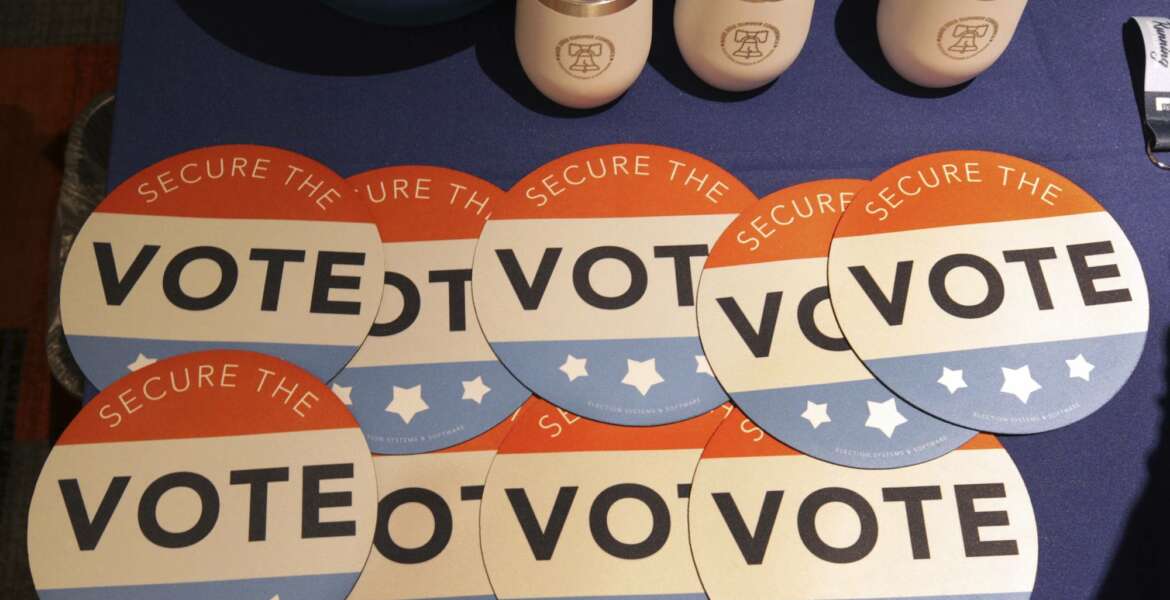 Computer mouse pads with Secure the Vote logo on them are seen on a vendor's table at a convention of state secretaries of state Saturday, July 14, 2018, in Philadelphia. Department of Homeland Security Secretary Kirstjen Nielsen spoke at the convention, an event that's usually a low-key affair highlighting voter registration, balloting devices and election security issues that don't get much public attention. But coming amid fresh allegations into Russia's attempts to sway the 2016 election, the sessions on election security have a higher level of urgency and interest. (AP Photo/Mel Evans)