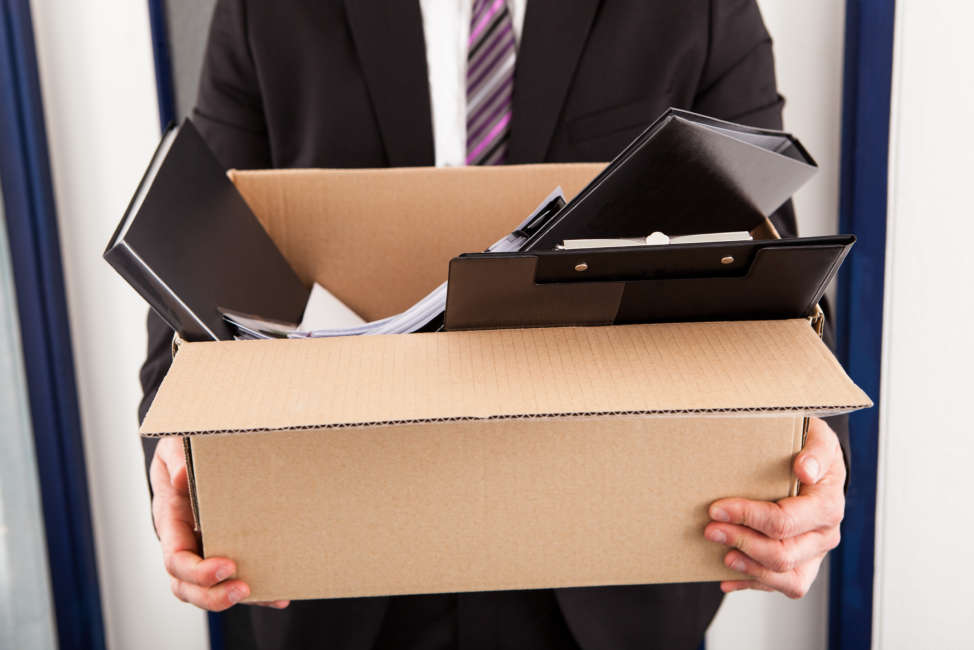 Portrait of young businessman holding cardboard in office