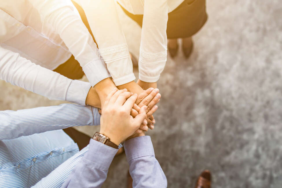 Close up top view of young business people putting their hands together. Stack of hands. Unity and teamwork concept.