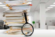 Stack of documents and magnifying glass on office table