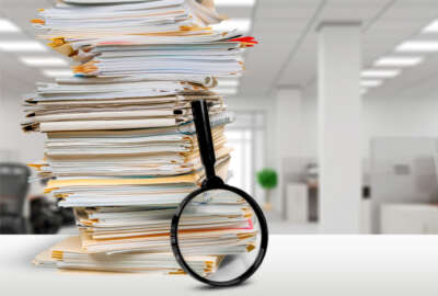 Stack of documents and magnifying glass on office table