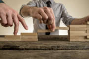 Businessman building staircase with wooden blocks to span a gap