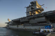 Tugboats move the aircraft carrier USS Enterprise away from the pier at Naval Station Norfolk