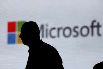 FILE - In this Nov. 7, 2017, file photo, a man is silhouetted as he walks in front of Microsoft logo at an event in New Delhi, India. Microsoft says it’s uncovered new Russian hacking attempts targeting U.S. political groups ahead of the midterm elections. The company said Tuesday, Aug. 21, 2018, that a hacking group tied to the Russian government created fake internet domains that appeared to spoof two conservative organizations: the Hudson Institute and the International Republican Institute. (AP Photo/Altaf Qadri, File)