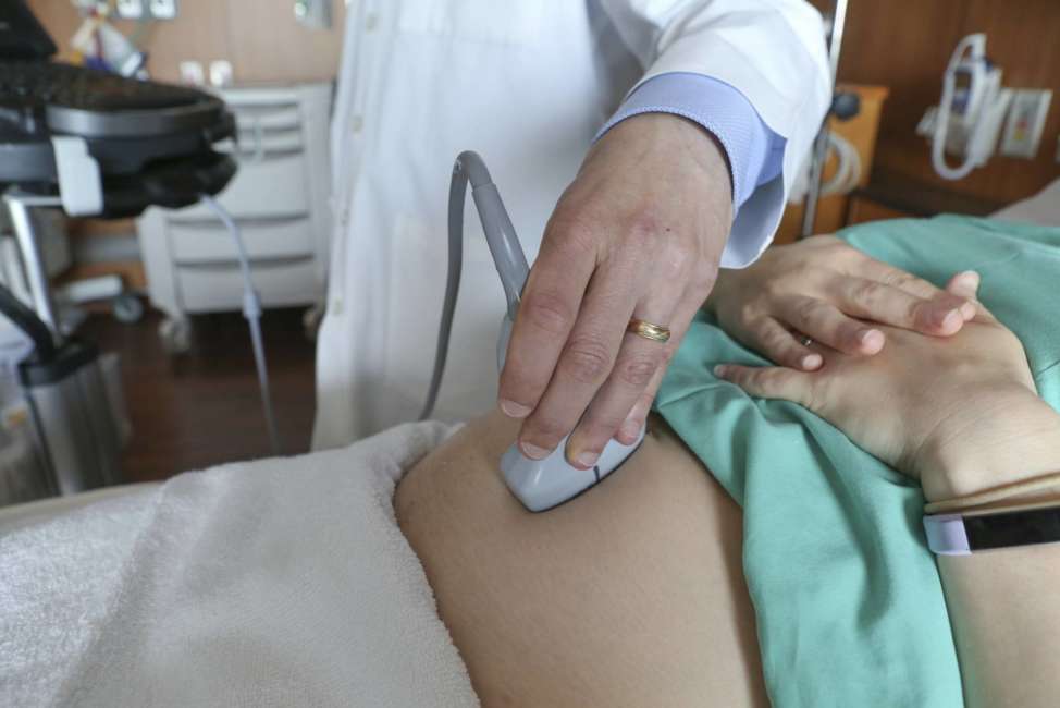 In this Aug. 7, 2018 photo, a doctor performs an ultrasound scan on a pregnant woman at a hospital in Chicago. According to a study released on Wednesday, Aug. 8, 2018, first-time mothers at low risk of complications were less likely to need a cesarean delivery if labor was induced at 39 weeks instead of waiting for it to start on its own. Their babies fared better, too. (AP Photo/Teresa Crawford)