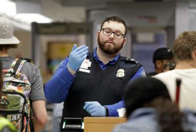 A TSA agent calls passengers forward for screening at Sea-Tac International Airport Friday evening, Aug. 10, 2018, in SeaTac, Wash. An airline mechanic stole an Alaska Airlines plane without any passengers and took off from Sea-Tac International Airport in Washington state on Friday night before crashing near Ketron Island, officials said. (AP Photo/Elaine Thompson)