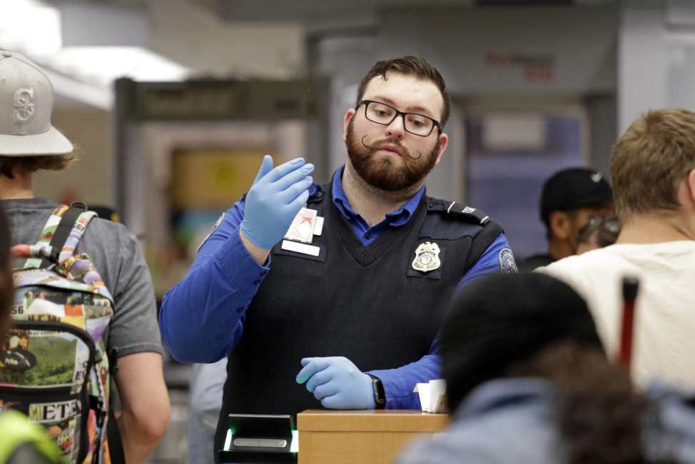 A TSA agent calls passengers forward for screening at Sea-Tac International Airport Friday evening, Aug. 10, 2018, in SeaTac, Wash. An airline mechanic stole an Alaska Airlines plane without any passengers and took off from Sea-Tac International Airport in Washington state on Friday night before crashing near Ketron Island, officials said. (AP Photo/Elaine Thompson)