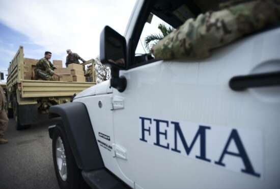 FILE - In this Oct. 5, 2017 file photo, Department of Homeland Security personnel deliver supplies to Santa Ana community residents in the aftermath of Hurricane Maria in Guayama, Puerto Rico. The U.S. Government Accountability Office said Tuesday, Sept. 4, 2018 that 54 percent of FEMA personnel were not qualified for their position in October 2017, a month after the Category 4 storm hit the U.S. territory.  (AP Photo/Carlos Giusti, File)