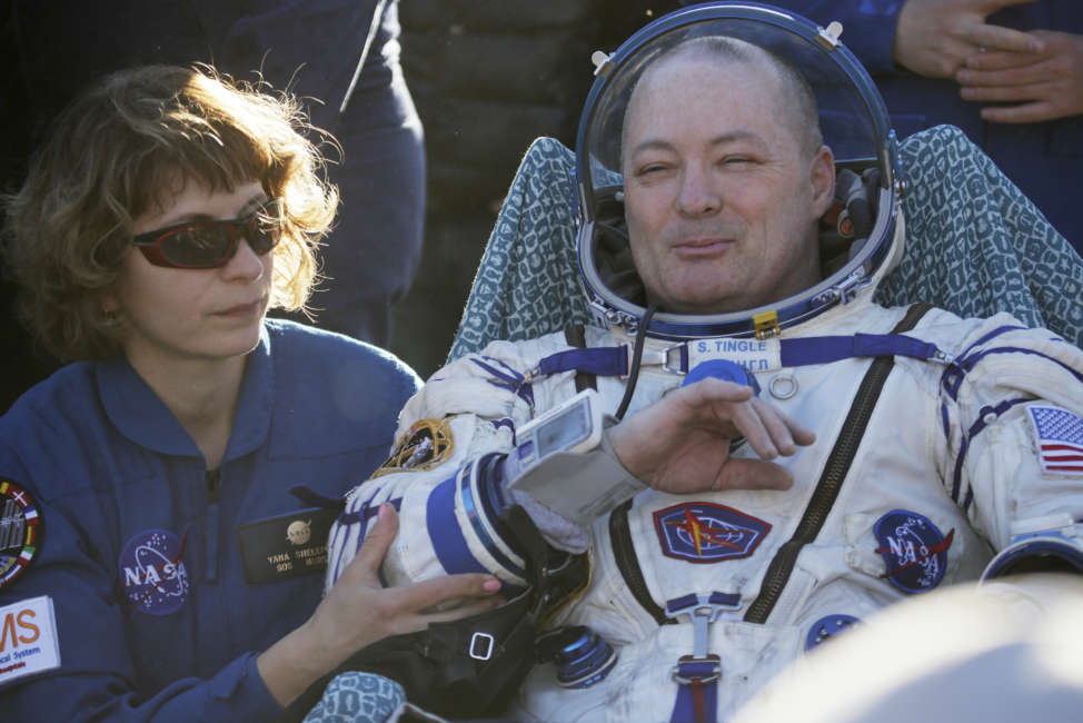 A NASA specialist helps U.S. astronaut Scott Tingle shortly after the landing of the Russian Soyuz MS-07 space capsule about 150 km (80 miles) south-east of the Kazakh town of Zhezkazgan, Kazakhstan, Sunday, June 3, 2018. A Soyuz space capsule with Russian cosmonaut Anton Shkaplerov, U.S. astronaut Scott Tingle and Japanese astronaut Norishige Kanai, returning from a mission to the International Space Station landed safely on Sunday on the steppes of Kazakhstan. (AP Photo/Dmitri Lovetsky, pool)