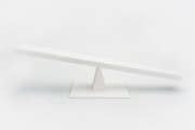 Close-up view of white wooden seesaw balancing isolated on grey