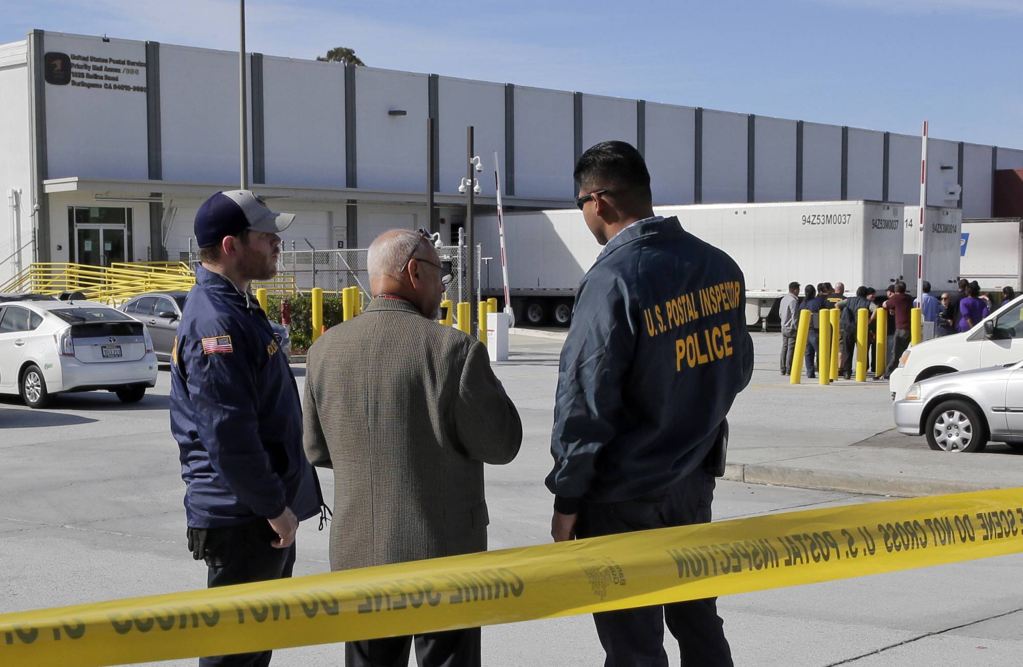 Postal inspectors confer outside of a postal facility in Burlingame, Calif., on Friday, Oct. 26. 2018. FBI spokesman Prentice Danner says a suspicious package seized at this facility near San Francisco and addressed to billionaire political activist Tom Steyer has several similarities to 13 explosive devices that were addressed to prominent Democrats across the country. When asked if authorities believe the package found Friday is related to the others, Danner said the 