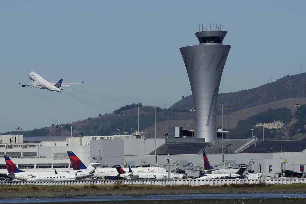 FILE - In this Oct. 24, 2107 file photo, the air traffic control tower is in sight as a plane takes off from San Francisco International Airport in San Francisco. Aviation-safety officials say a close call last year highlights the need for faster reporting of dangerous incidents before evidence is lost. The National Transportation Safety Board issued a final report Thursday, Oct. 11, 2018  on the July 2017 close call in which an Air Canada jet nearly crashed into planes lined up on the ground at San Francisco International Airport. (AP Photo/Jeff Chiu, File)